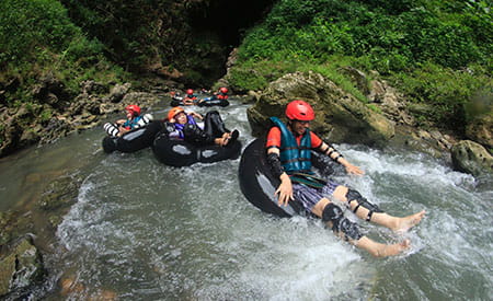 group of travelers floating down rapids in inner tubes