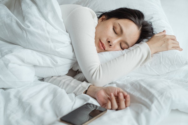 person sleeping on a bed with a phone