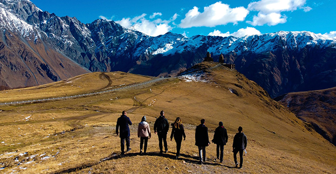 group in travel abroad program walking toward snowy mountains