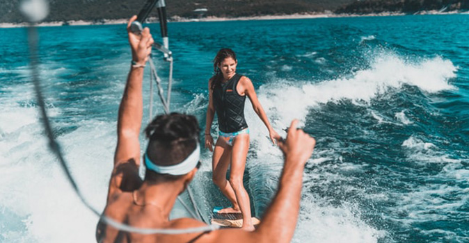 summer vacation ideas; wakeboarding couple on water