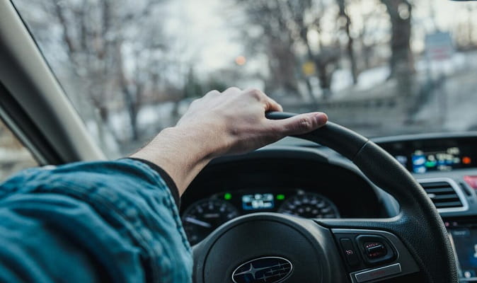 hand resting on car steering wheel