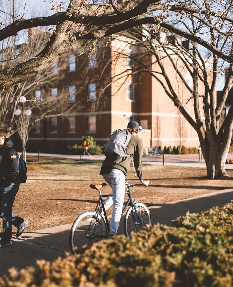 student biking on college campus