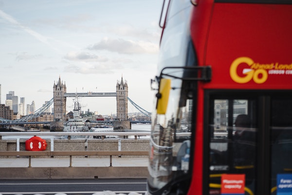 bus passing by with tower bridge in the background in london
