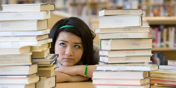 girl looking at stack of books