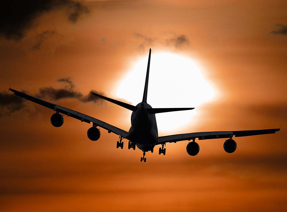 airplane-flying-through-orange-sky-carbon-offsetting-flights