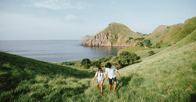 honeymoon-planning-checklist-image-couple-walking-through-green-cliffside