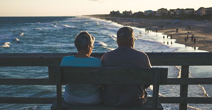 seniors-sitting-on-a-bench-by-the-ocean-outside-the-us