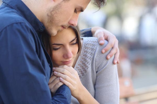 man-comforting-his-sad-mourning-friend-embracing-her-in-a