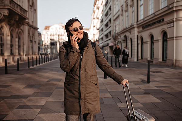man-on-phone-while-traveling-with-luggage man-on-phone-while-traveling-with-luggage