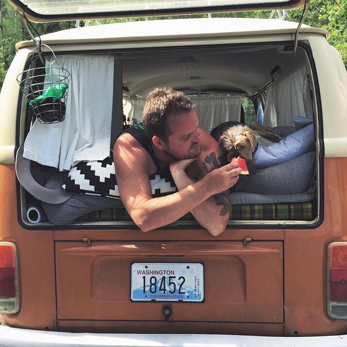 editorial only - man and dog resting in back of van, travel